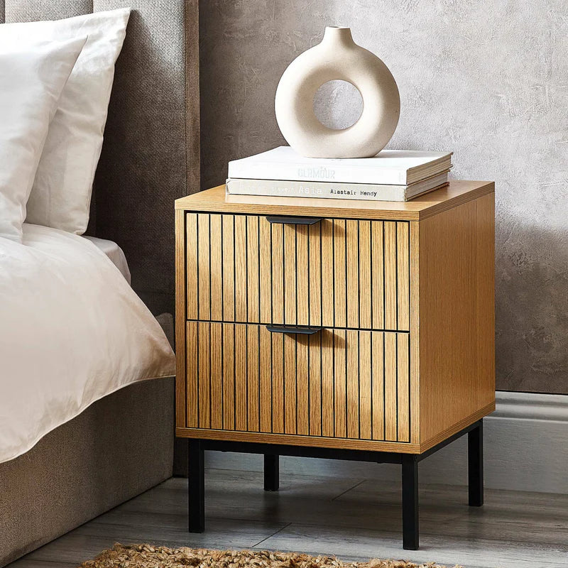 Wooden nightstand with decorative items next to a bed in a bedroom setting