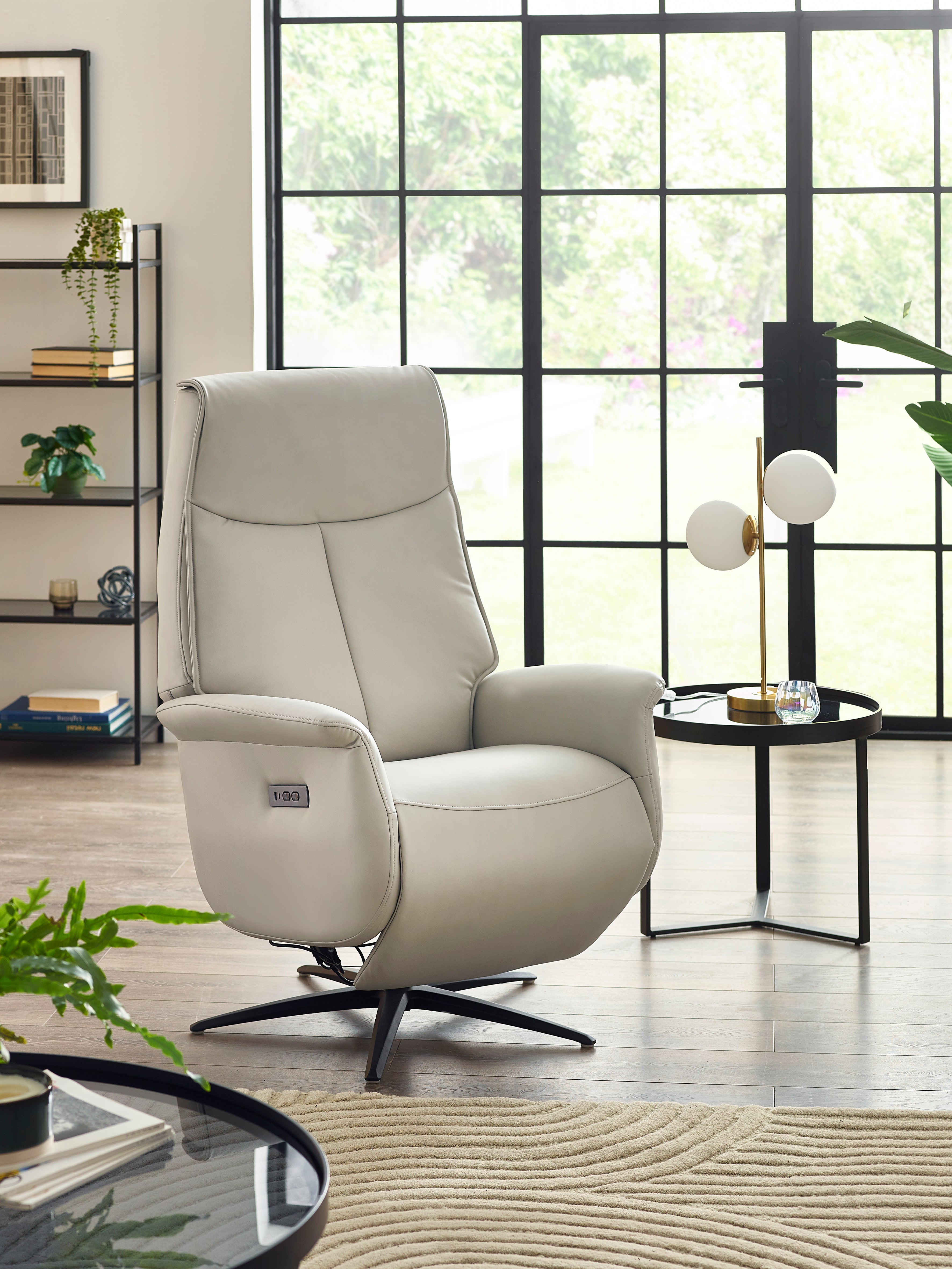 Beige recliner chair in a modern living room with large windows.