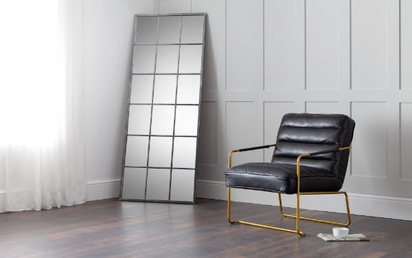Modern black leather chair with gold legs in a minimalistic room.