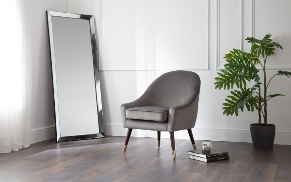 Gray armchair in a room with a large mirror and a plant.