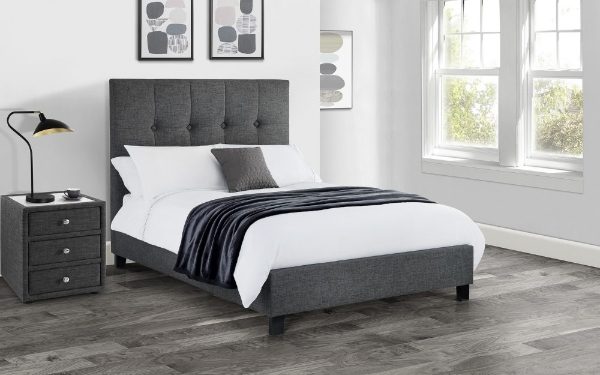 Gray upholstered bed with white bedding in a bedroom setting.