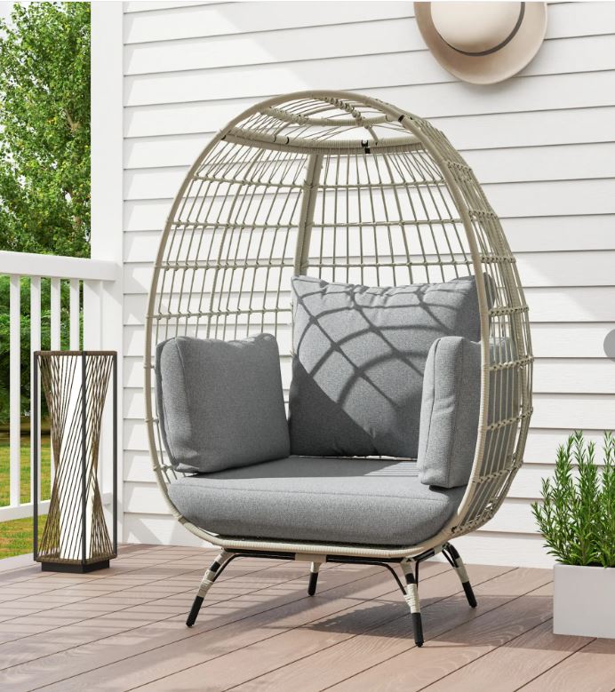 Egg-shaped wicker chair with gray cushions on a wooden deck.