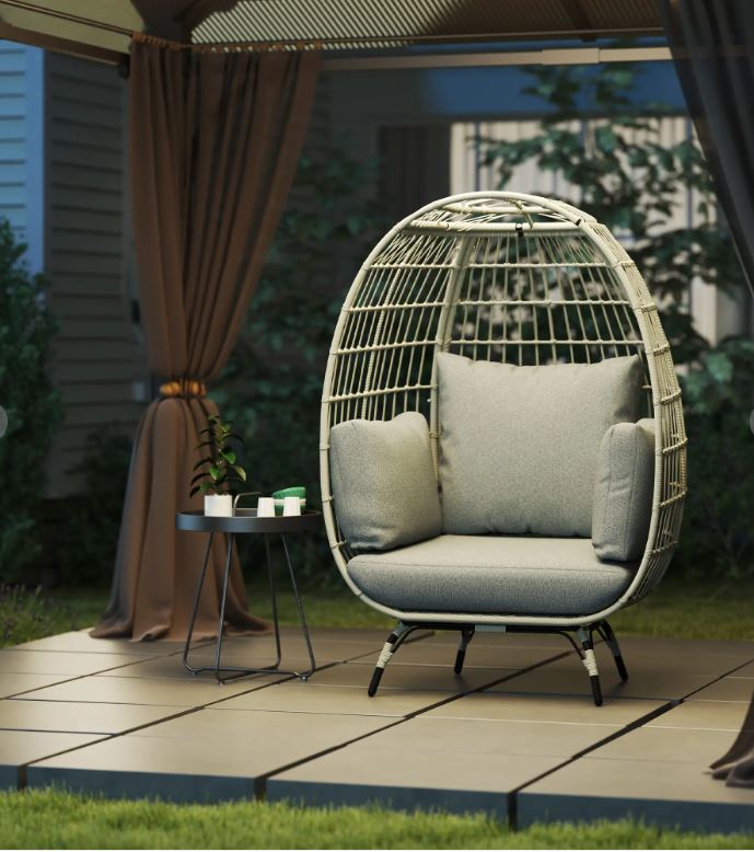 Egg-shaped wicker chair with cushions on a wooden deck