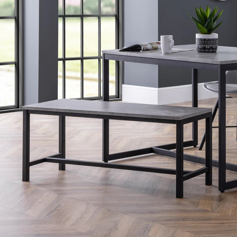 Two black metal tables with gray tops in a room with large windows.
