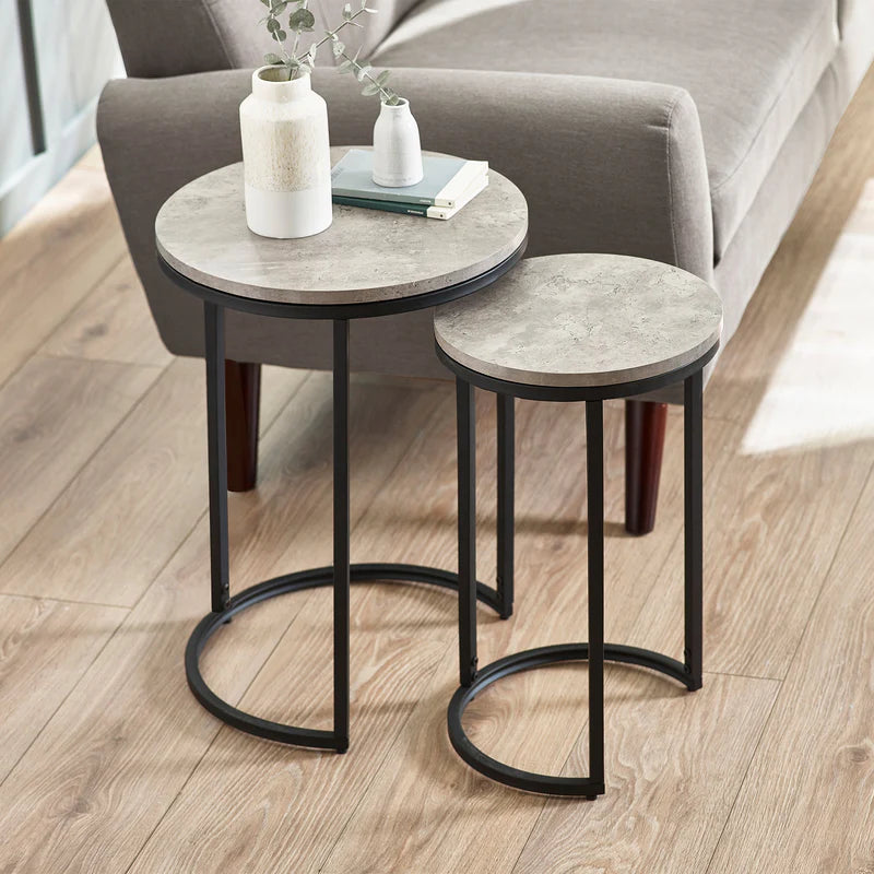 Set of two round side tables with marble-like tops and black metal legs in a living room setting.