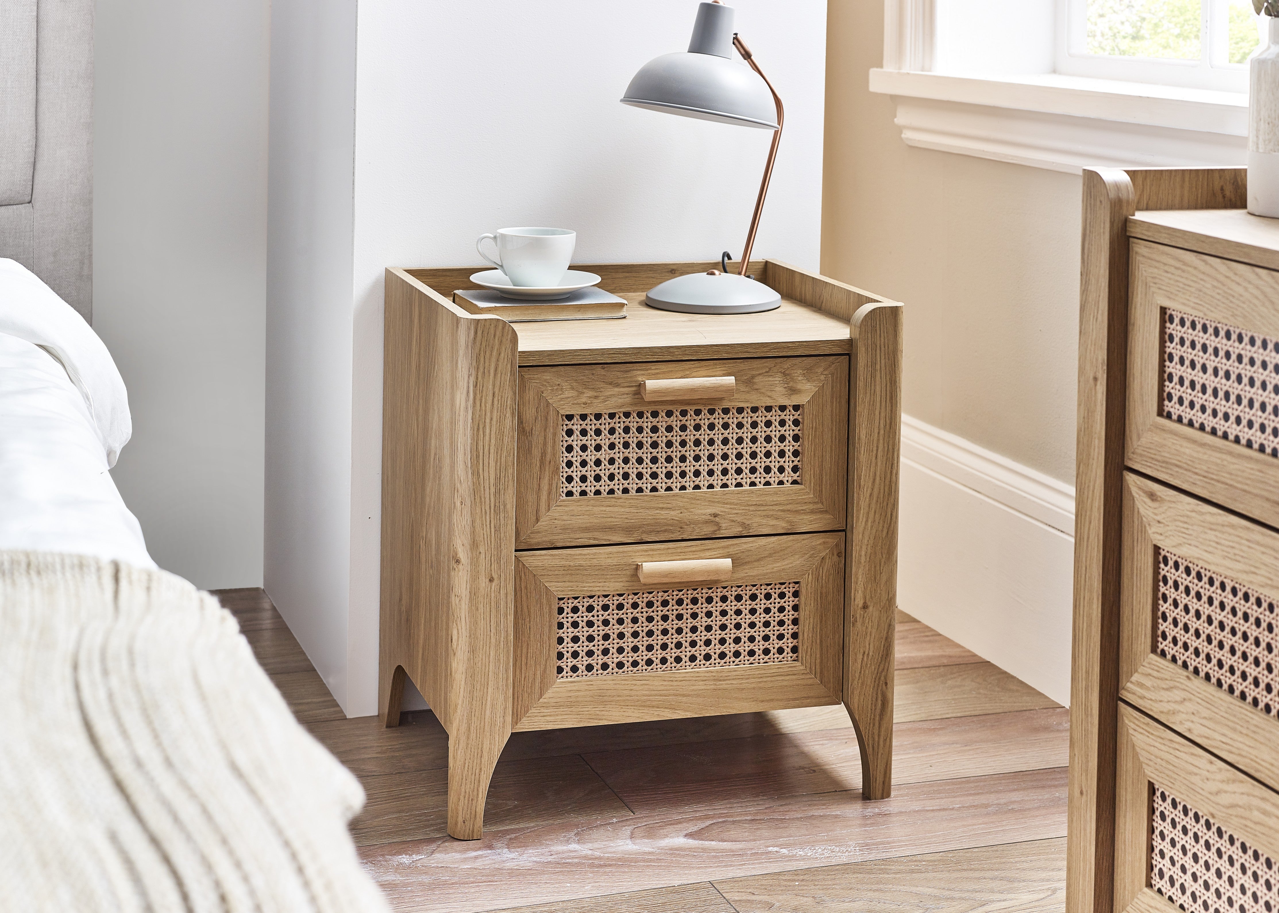 Wooden nightstand with a lamp and cups in a bedroom setting
