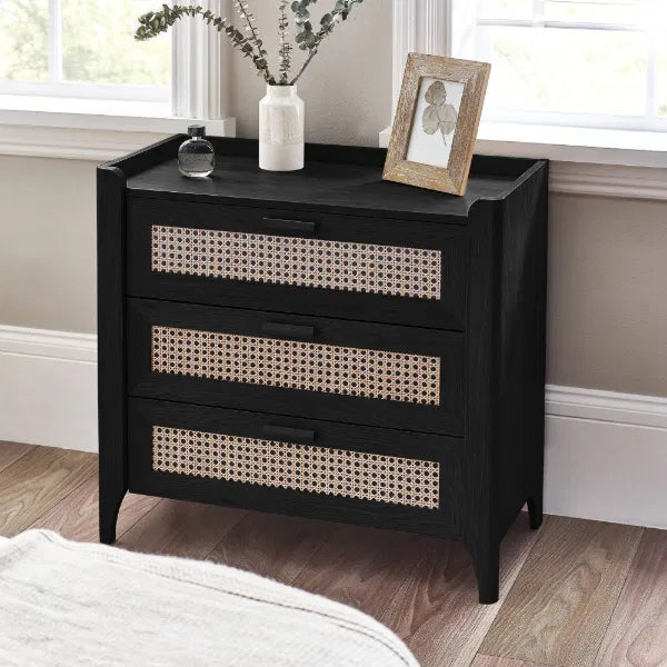 Black dresser with wicker drawers in a room with a window and rug.