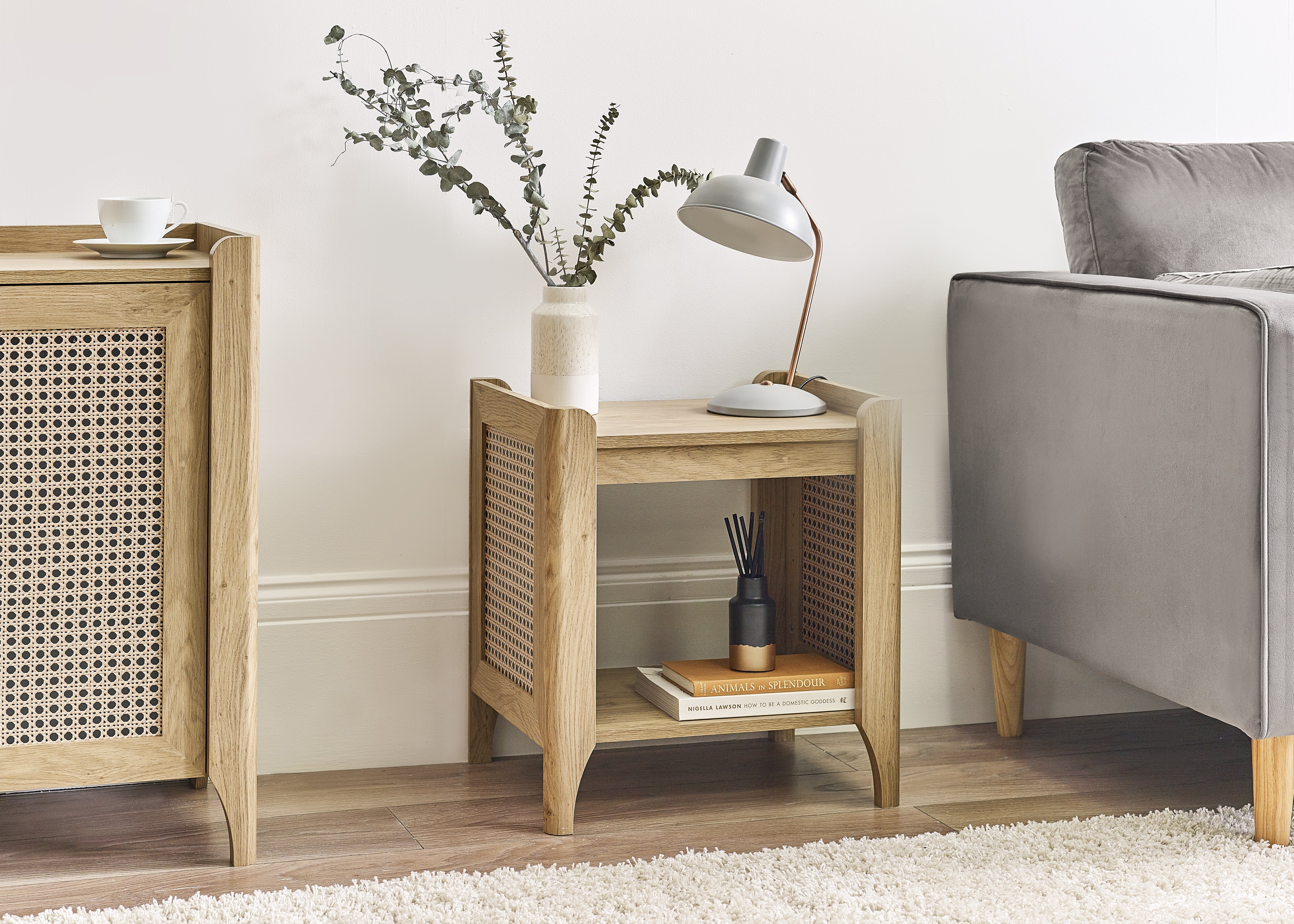 Wooden side table with decorative items next to a gray sofa in a living room setting.