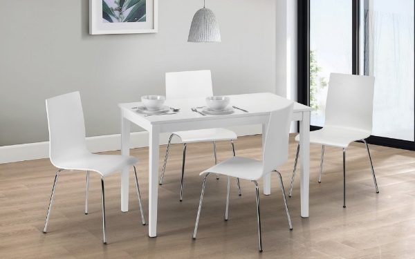 White dining table with four chairs in a room with a gray wall and large window.