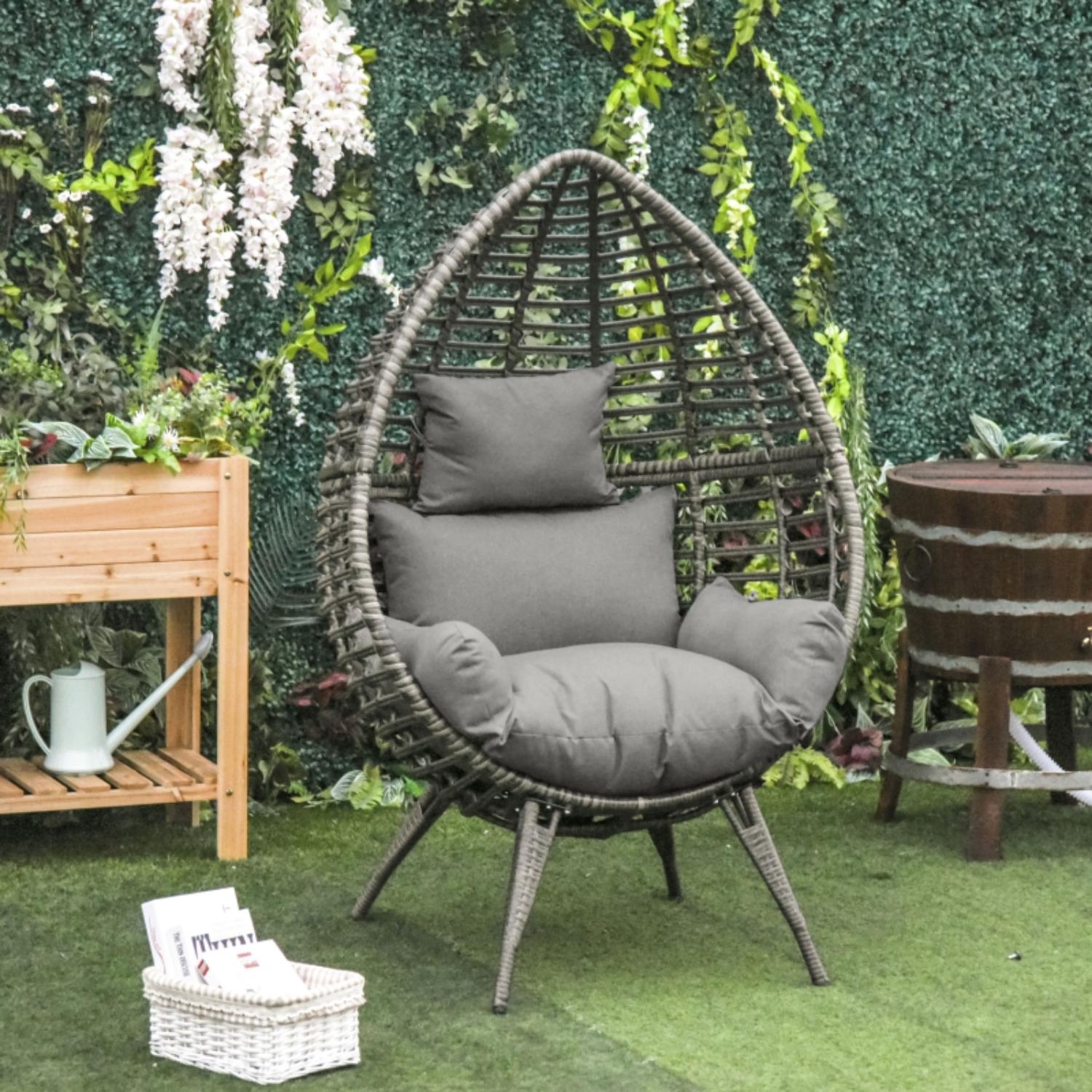 Wicker egg chair with gray cushions in a garden setting