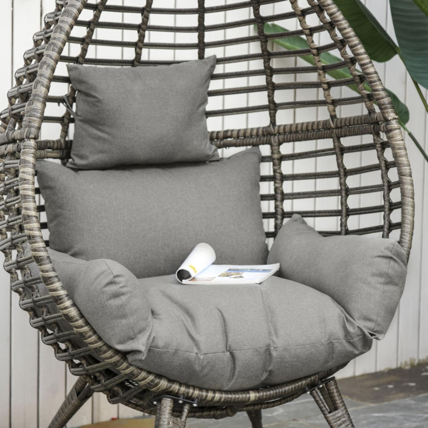 Hanging chair with gray cushions and a magazine on a wooden floor.