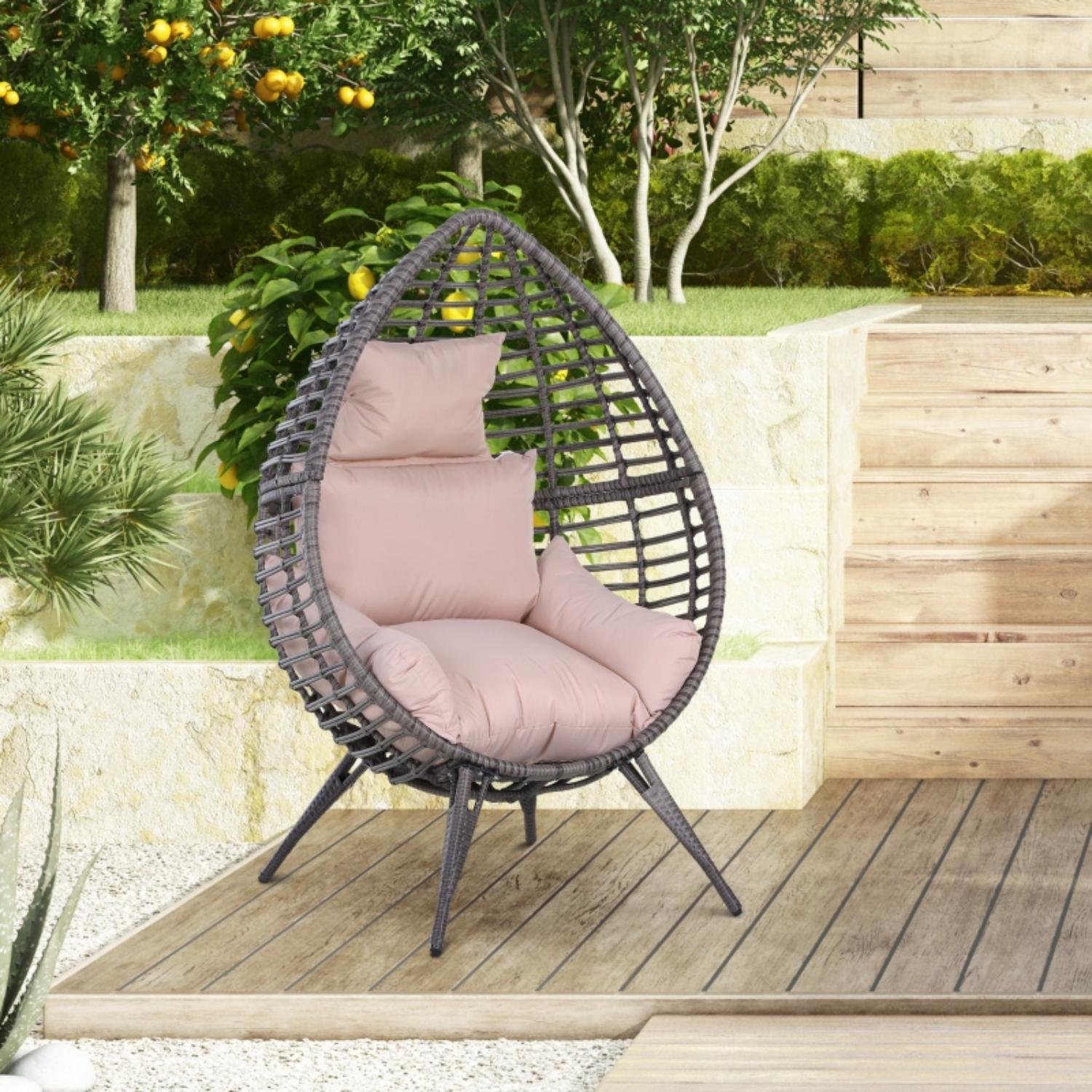 Wicker egg-shaped chair with pink cushions on a wooden deck