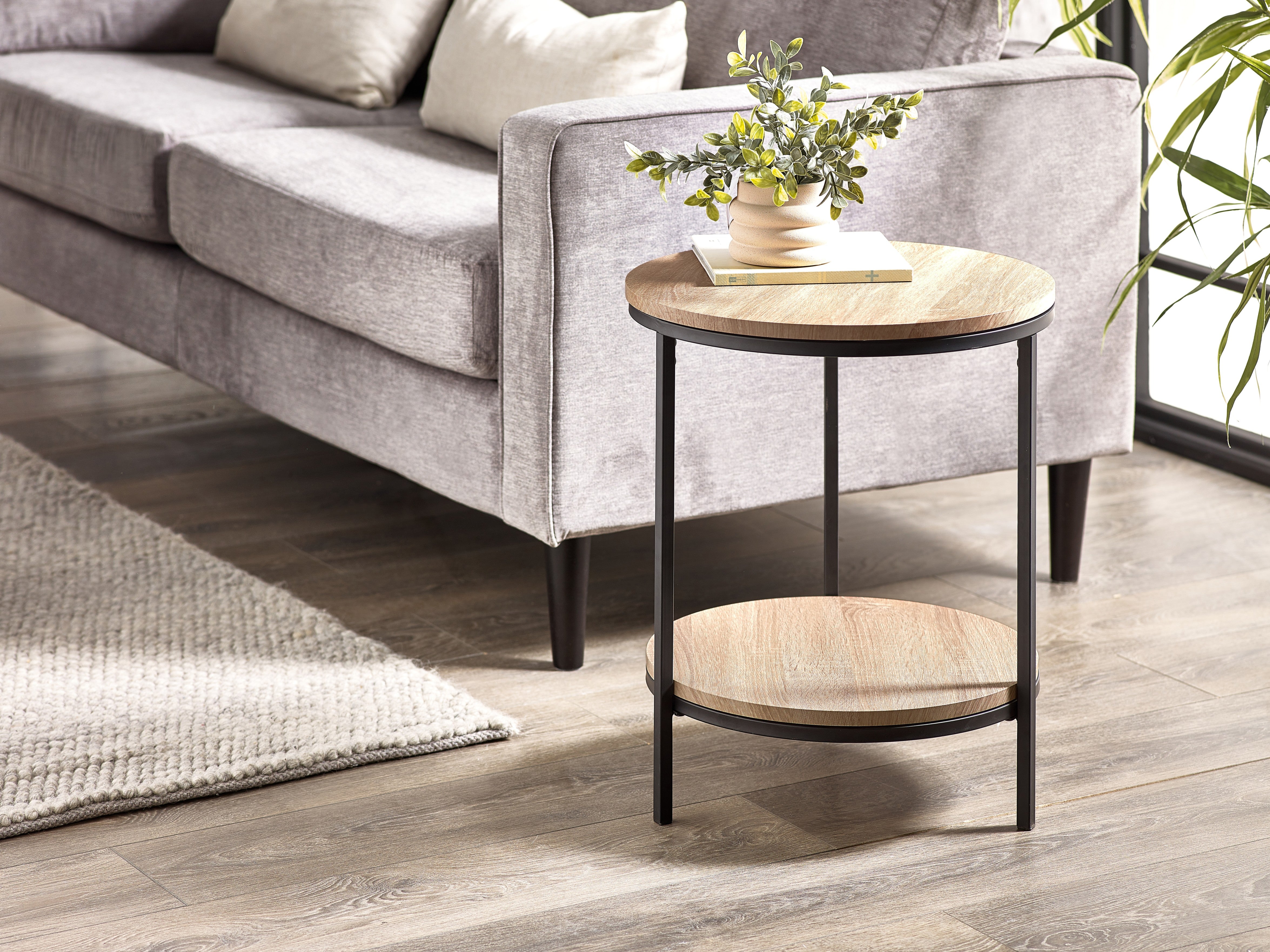 Round side table with wooden top and black metal frame in a living room setting.
