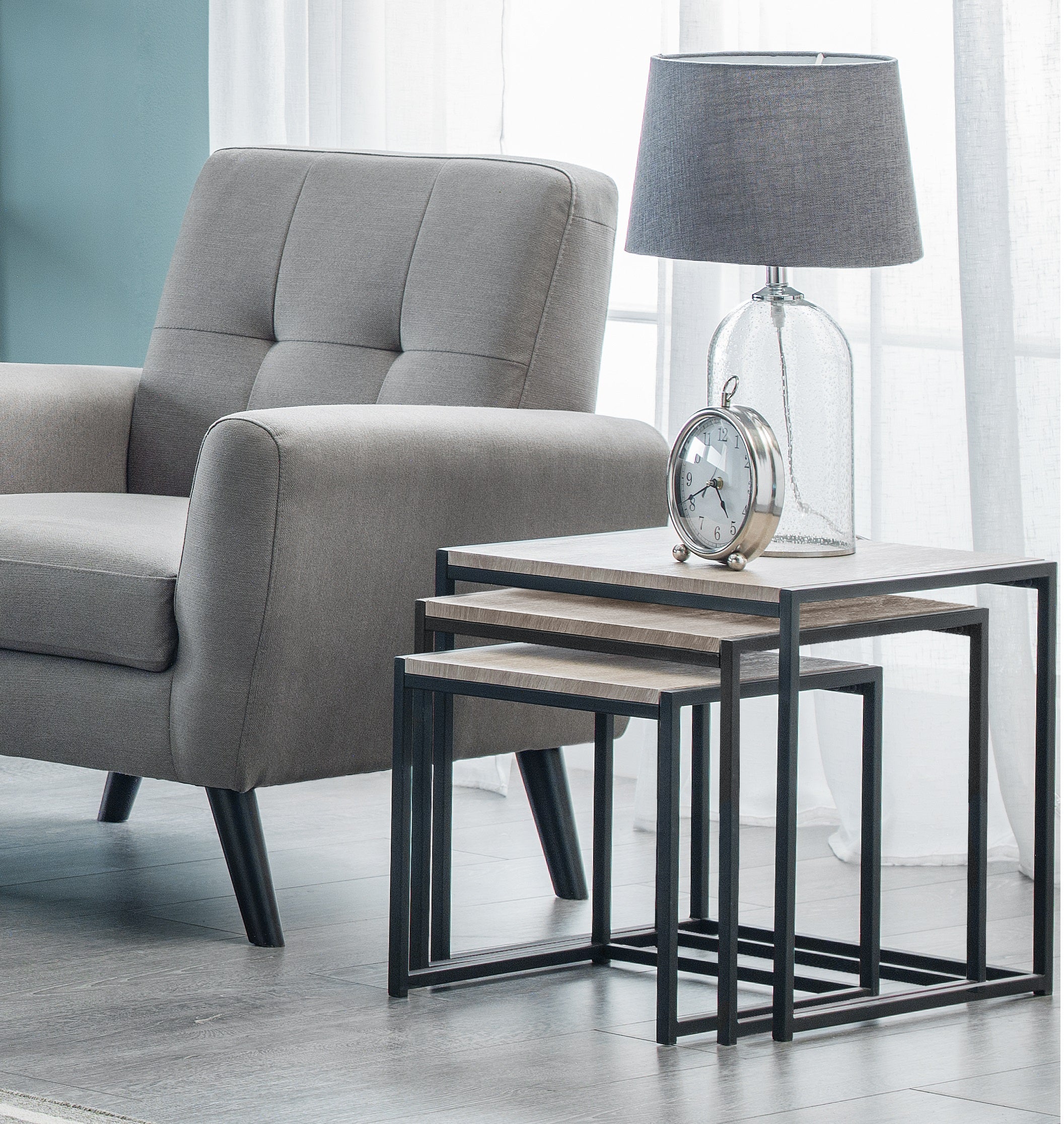 Gray armchair with nesting tables and a lamp in a modern living room.