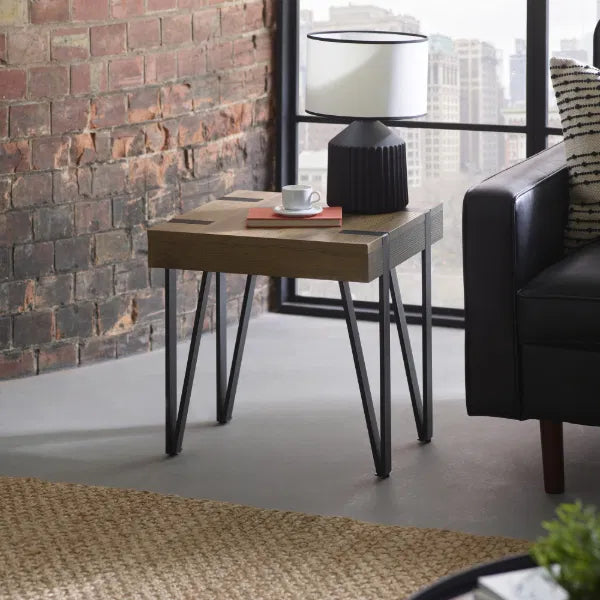 Wooden side table with a lamp and cup against a brick wall in a modern living room.