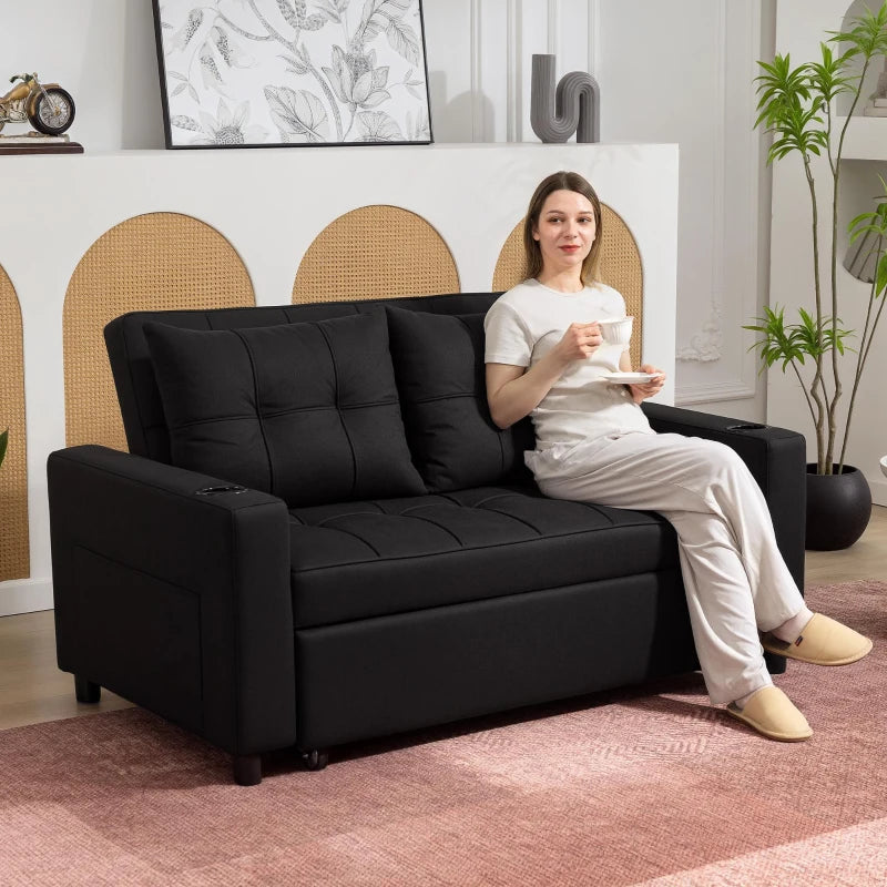 Woman sitting on a black sofa in a living room holding a cup.