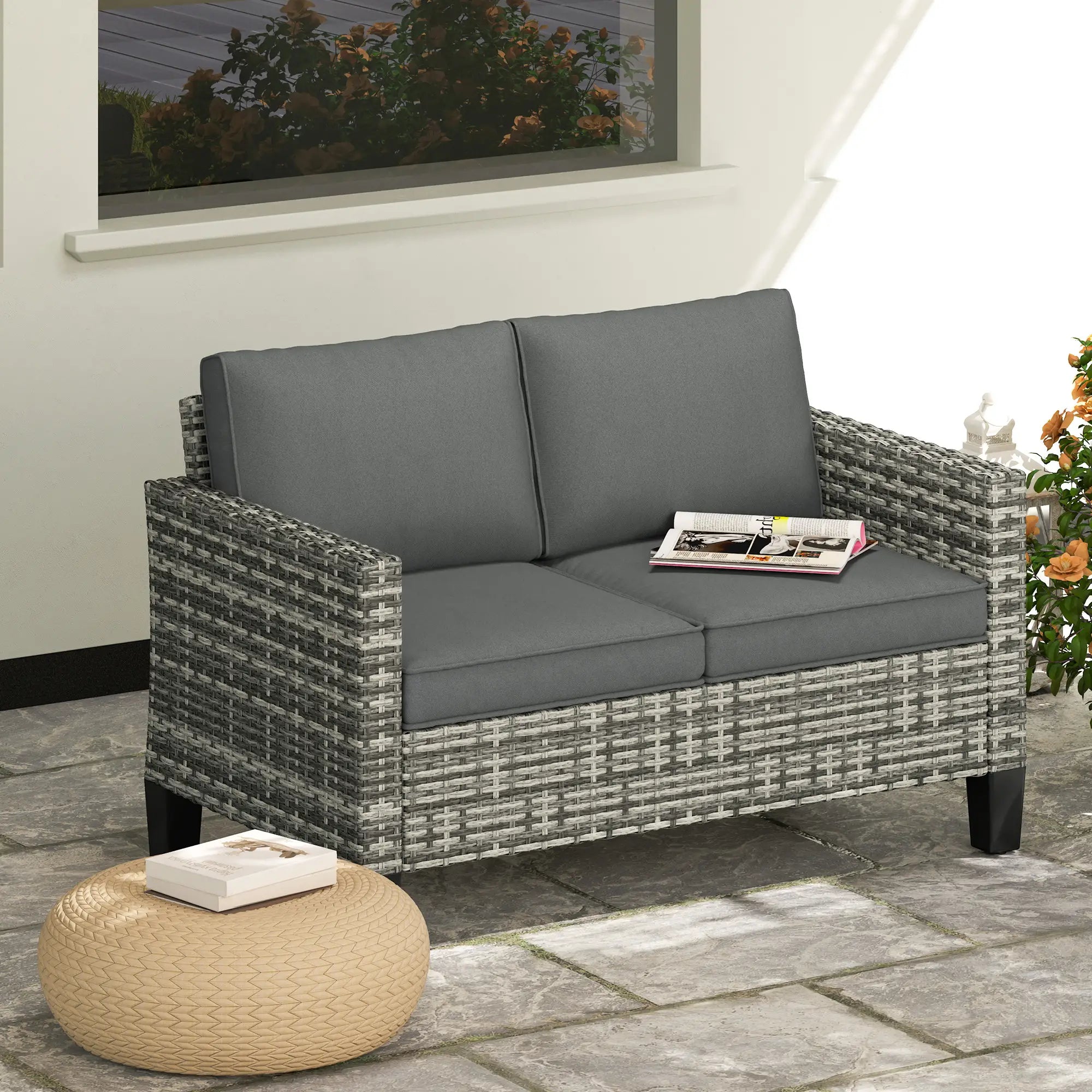 Gray outdoor sofa with cushions on a stone patio, next to a small table.
