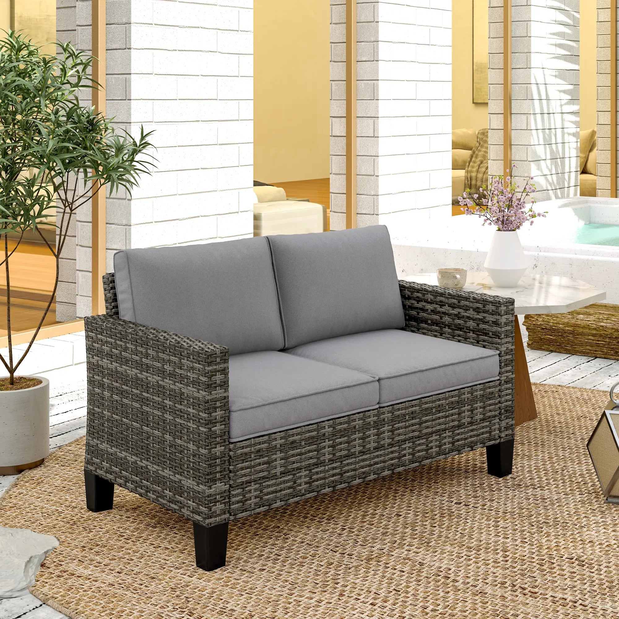Gray cushioned outdoor loveseat with wicker frame on a patio