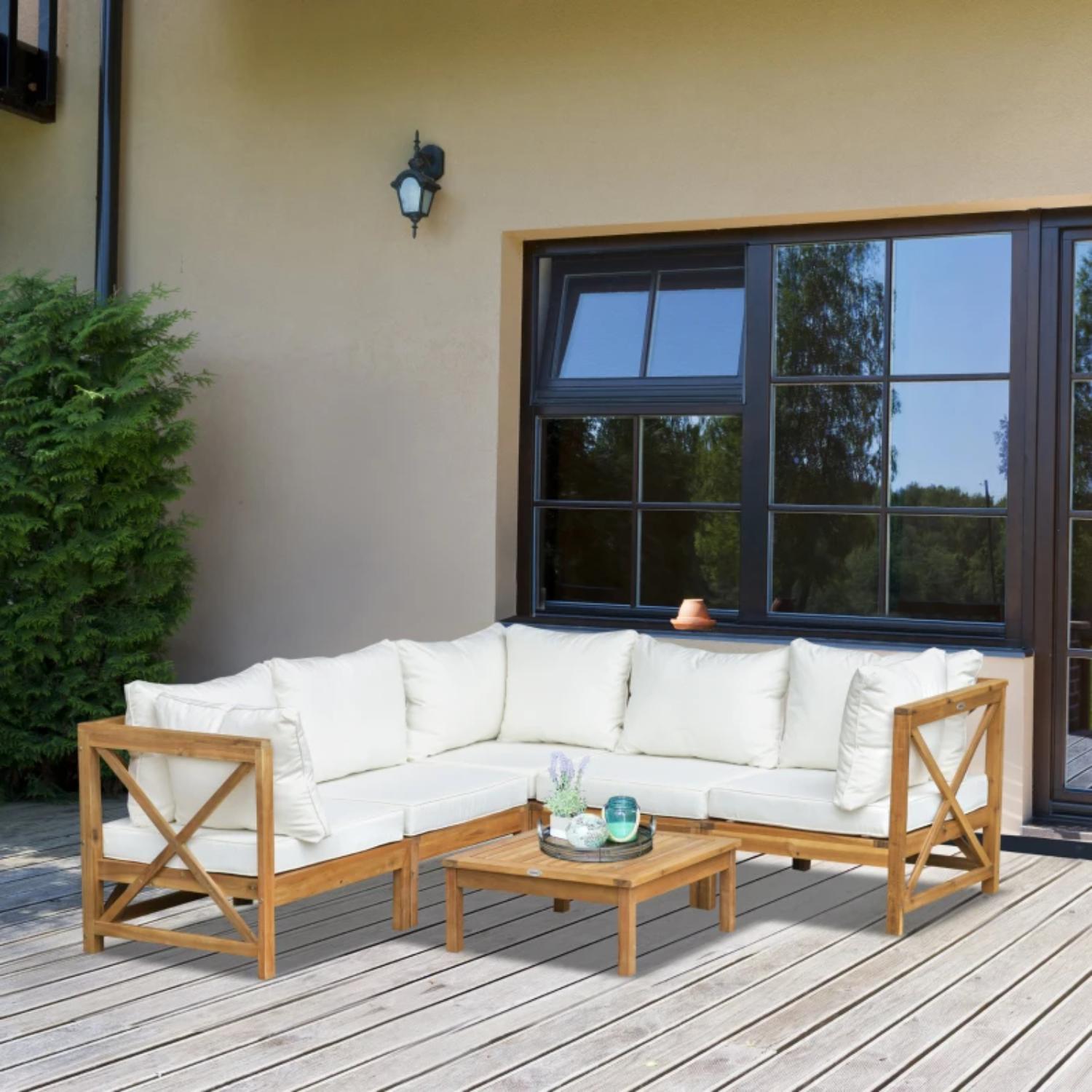 Outdoor patio set with white cushions and wooden frame on a deck.