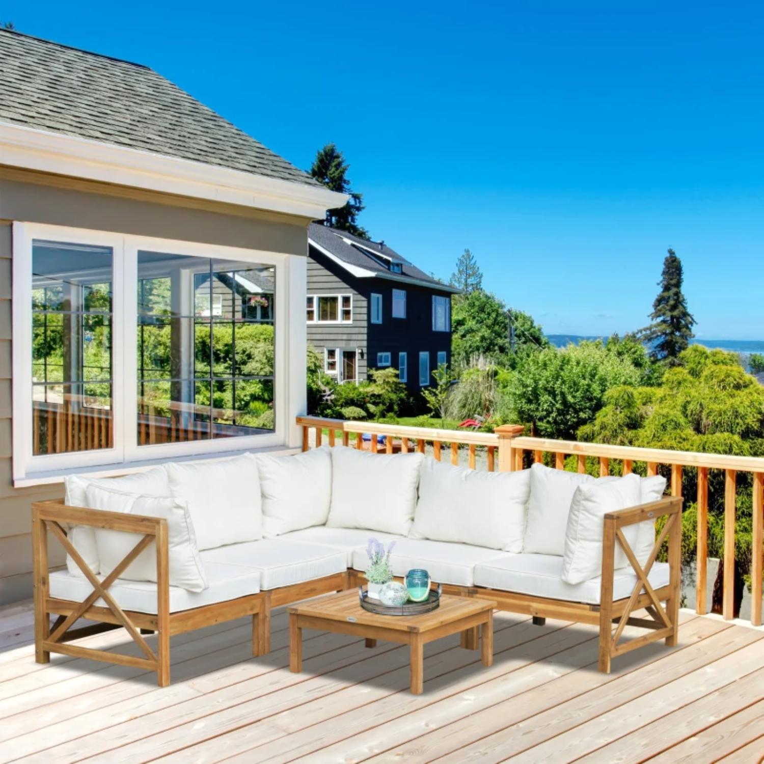Wooden outdoor sofa set with white cushions on a deck with a scenic view.