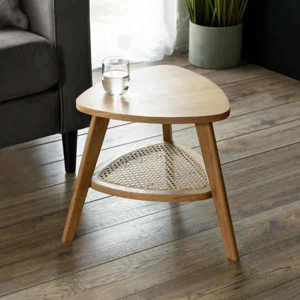Wooden side table with a glass of water on a wooden floor in a living room setting.