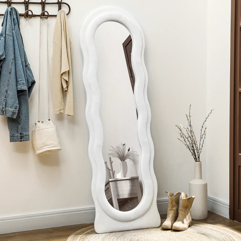 White wavy mirror in a room with clothes and decor items.