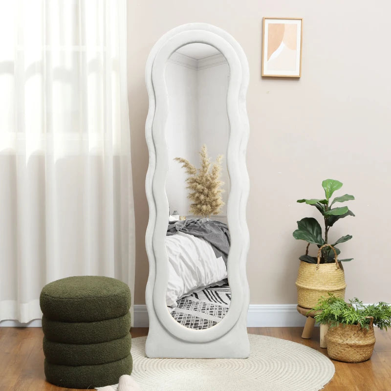 White floor mirror in a room with plants and a green ottoman.