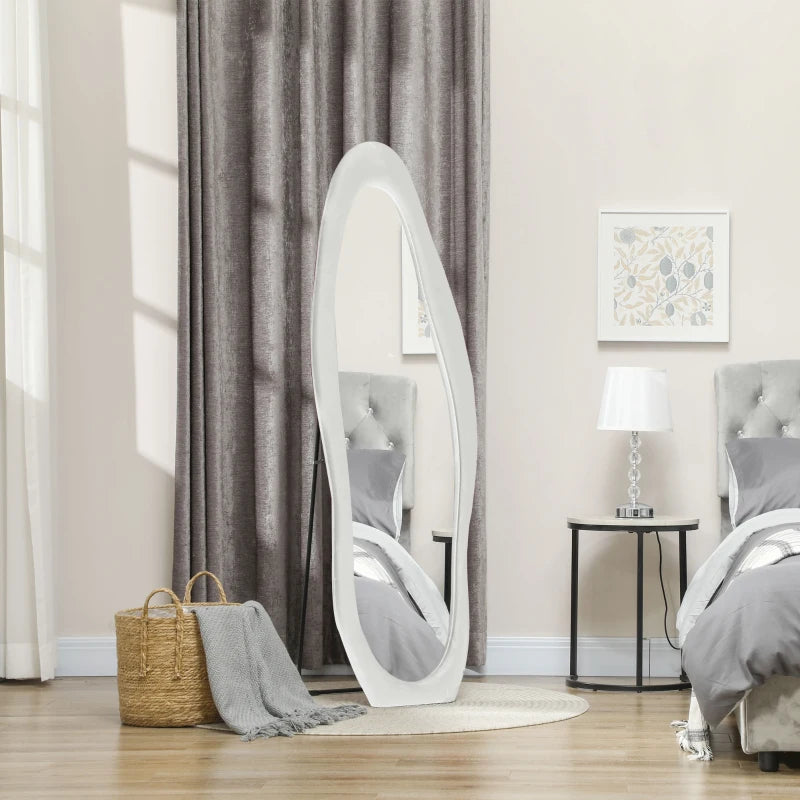 White oval mirror leaning against a wall in a bedroom setting.