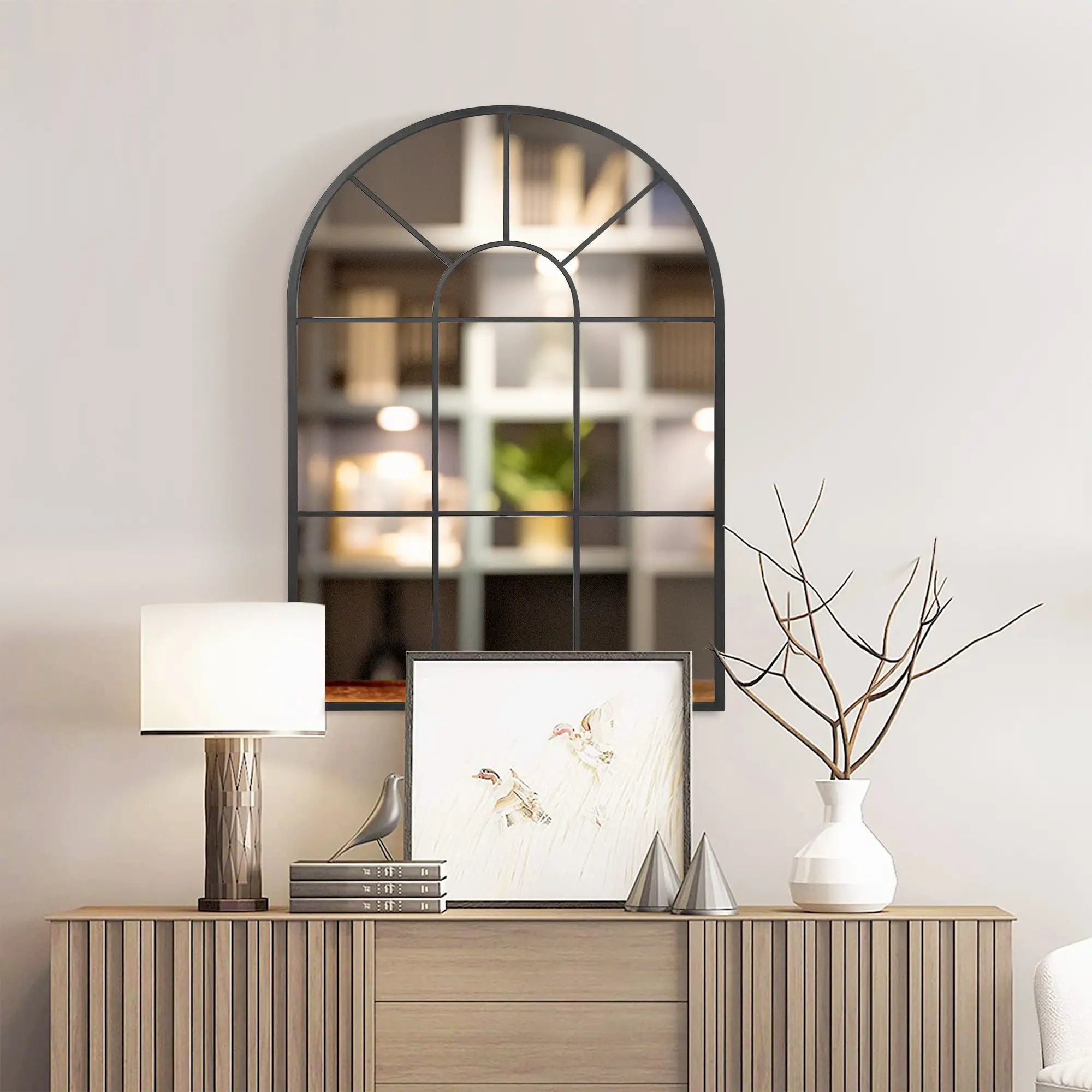 Decorative mirror above a wooden console table with a lamp, framed picture, and vase.
