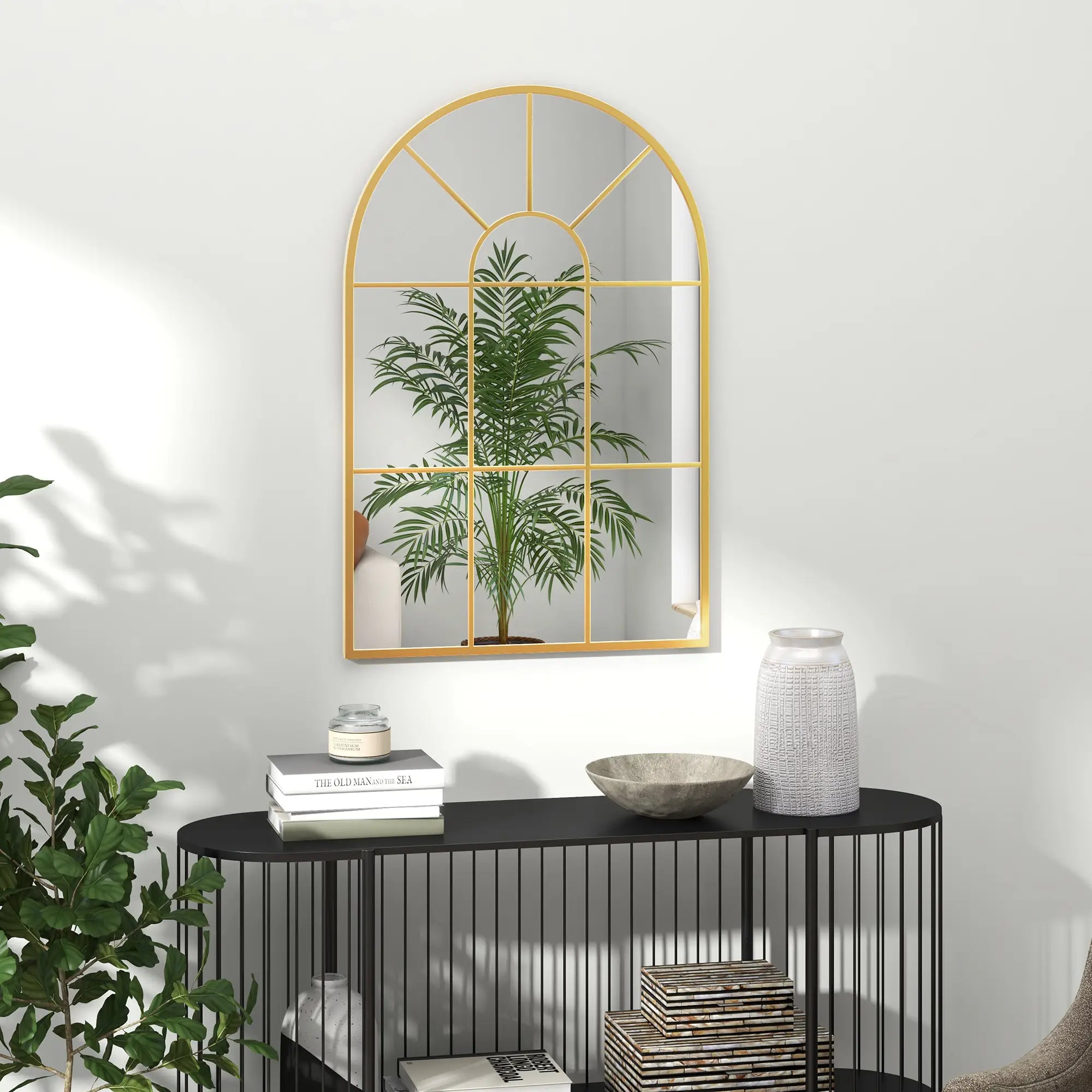 Decorative mirror with gold frame on a white wall above a black console table with decorative items.